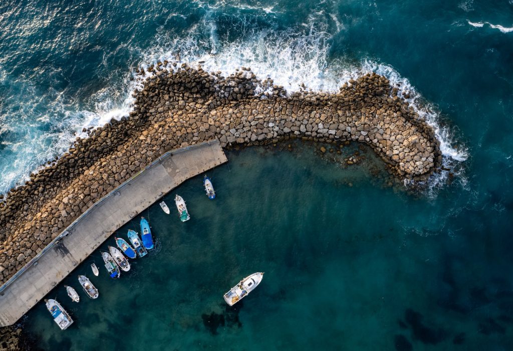 Drone aerial fishing harbour with boats stormy waves, blue sea